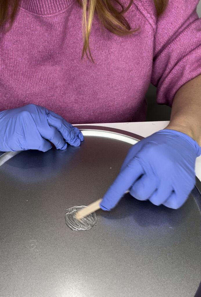 Woman testing out rhinestone adhesive to find the strongest glue for metal